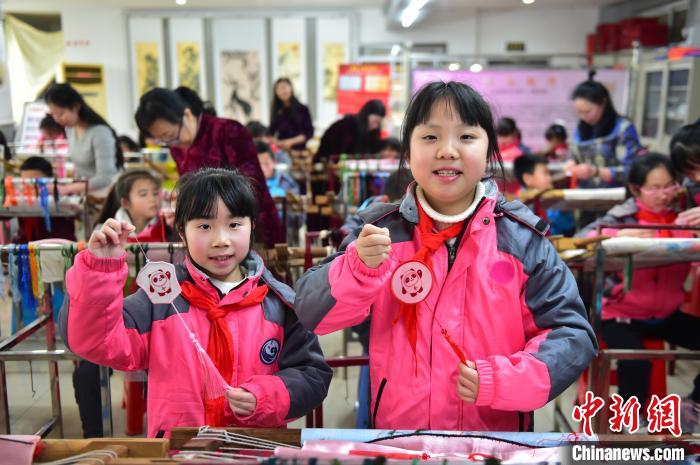 圖為小學(xué)生展示繡制好的2022年北京冬奧會(huì)吉祥物“冰墩墩”形象?！∮髟屏?攝