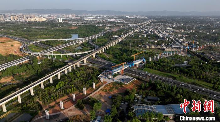 航拍正在建設(shè)的跨越成都繞城高速公路連續(xù)梁施工現(xiàn)場，旁邊依次為已運(yùn)營的成渝高速鐵路和機(jī)場高速公路?！⒅铱?攝