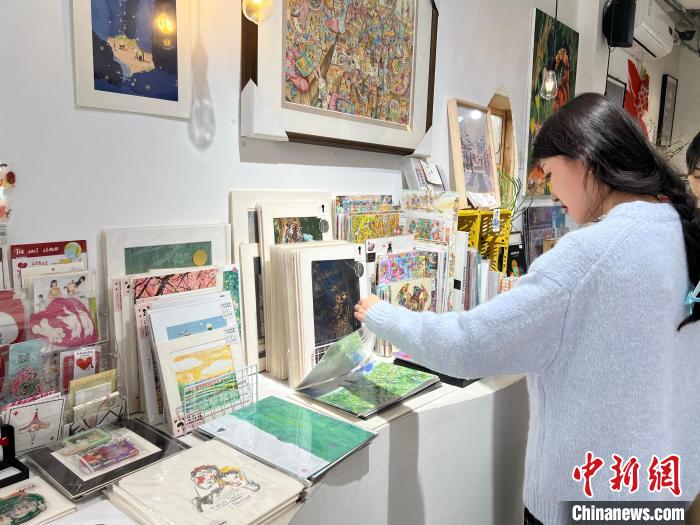 圖為藝術(shù)品商店內(nèi)，顧客挑選插畫作品?！＄婌?攝