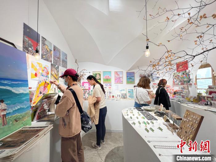 圖為藝術(shù)品商店內(nèi)，顧客挑選插畫作品?！＄婌?攝