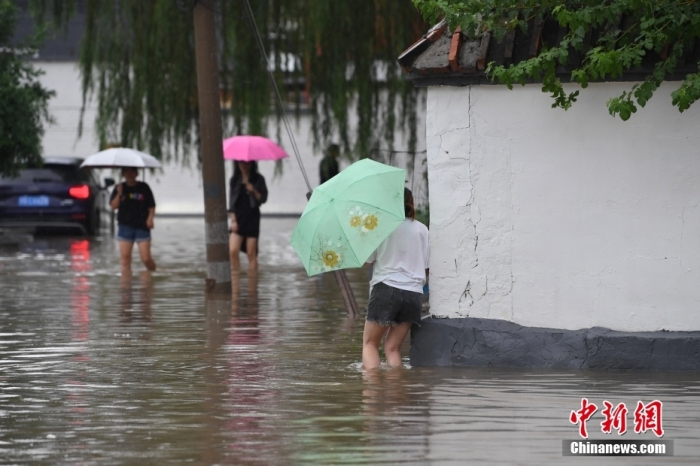 7月31日，市民行走在雨中的北京房山區(qū)瓦窯頭村。北京市氣象臺(tái)當(dāng)日10時(shí)發(fā)布分區(qū)域暴雨紅色預(yù)警信號(hào)。北京市水文總站發(fā)布洪水紅色預(yù)警，預(yù)計(jì)當(dāng)日12時(shí)至14時(shí)，房山區(qū)大石河流域?qū)⒊霈F(xiàn)紅色預(yù)警標(biāo)準(zhǔn)洪水。<a target='_blank' href='/'><p  align=
