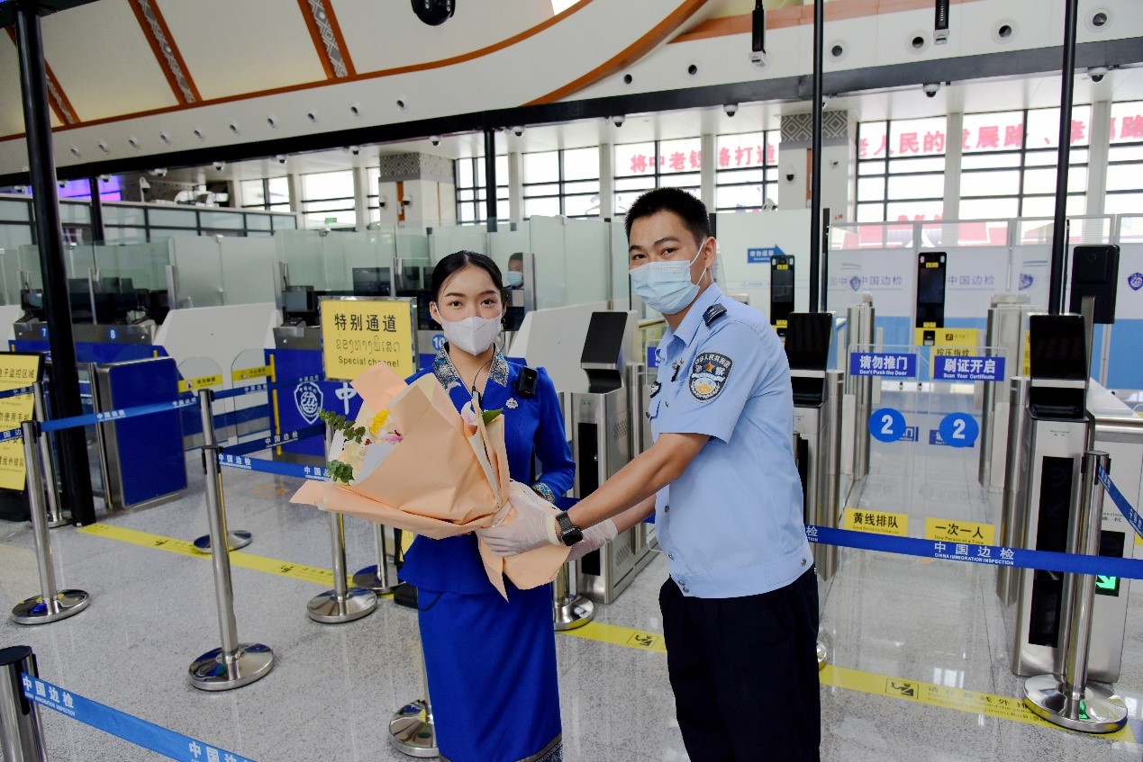 磨憨出入境邊防檢查站民警為中老鐵路第100萬名出入境旅客，D888次國際旅客列車?yán)蠐爰藙?wù)員森達(dá)拉·妮緹婭（Sengdala Nitiya），送上鮮花。黃遠(yuǎn)飛 攝