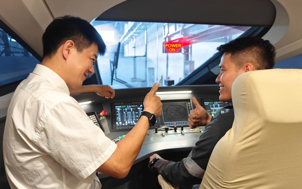 8月25日，在印度尼西亞萬隆的雅萬高鐵德卡魯爾動車所內(nèi)，中國師傅穆振（左）在向印尼火車司機(jī)塞蒂亞萬講解動車組出庫前的上電作業(yè)。
