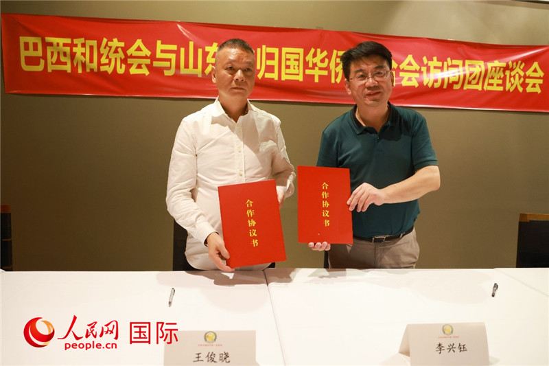 中國僑聯(lián)副主席、山東省僑聯(lián)主席李興鈺（右）與巴西和統(tǒng)會會長王俊曉簽署合作協(xié)議書。人民網(wǎng)記者 陳海琪攝