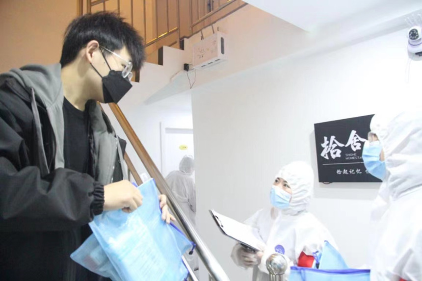 社區(qū)工作人員和志愿者身穿防護(hù)服上門送馬應(yīng)龍大健康防疫包。徐帥攝