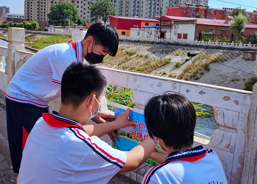 徐水小學(xué)學(xué)雷鋒志愿者在瀑河河邊張貼防溺水警示標(biāo)語(yǔ)。 徐水區(qū)委宣傳部供圖