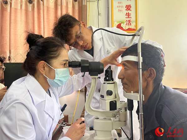 王紅英（左）和團隊成員為達熱村村民檢查眼睛。人民網(wǎng)記者 杜燕飛攝