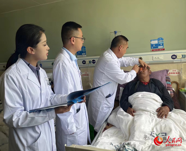 董光明（左三）帶領醫(yī)生對患者進行術前檢查。人民網(wǎng)記者 杜燕飛攝