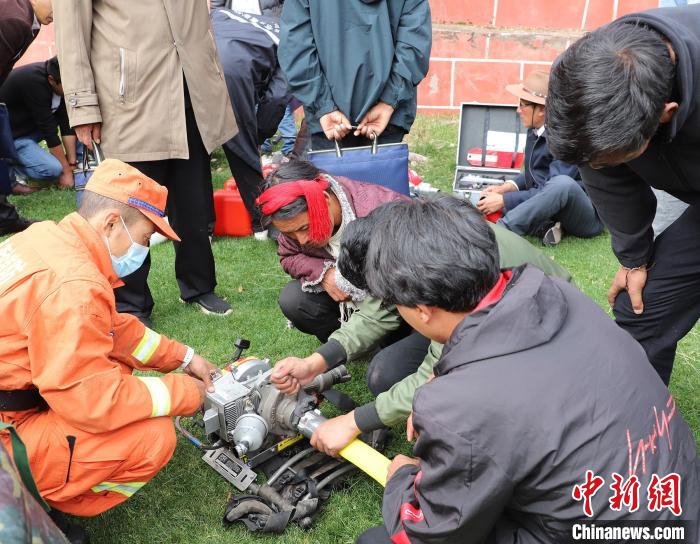 圖為森林消防員為護(hù)林員講解滅火裝備的使用方法?！〔际猩窒乐ш?duì) 供圖