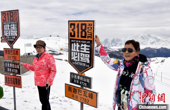 圖為5月14日，西藏林芝色季拉山觀景臺(tái)，游客與南迦巴瓦峰合影。　李林 攝