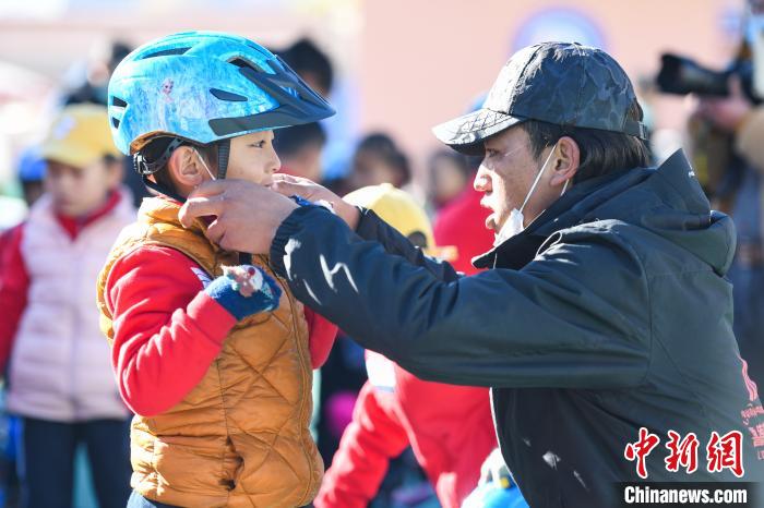 圖為拉薩市實(shí)驗(yàn)幼兒園孩子在教練的幫助下穿戴頭盔?！『闻罾?攝