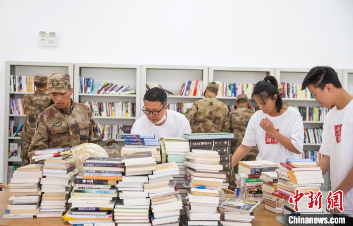 圖為志愿者們和邊防戰(zhàn)士整理圖書?！詵| 攝