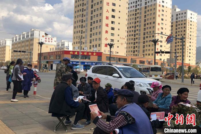 圖為會澤縣城易地扶貧搬遷安置點(diǎn)內(nèi)，老人們聚在廣場上聊天，身后是他們的新家?！】姵?攝