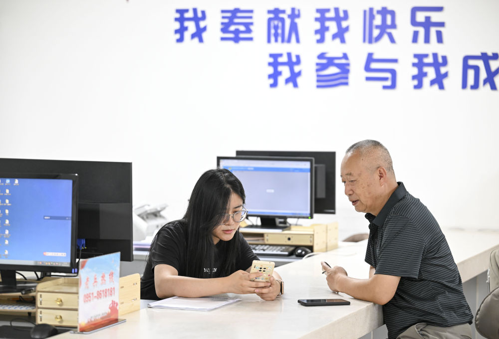 2024年6月20日，在寧夏銀川市金鳳區(qū)長城花園社區(qū)黨群服務(wù)中心，工作人員幫助居民辦理業(yè)務(wù)。圖片來源 新華社
