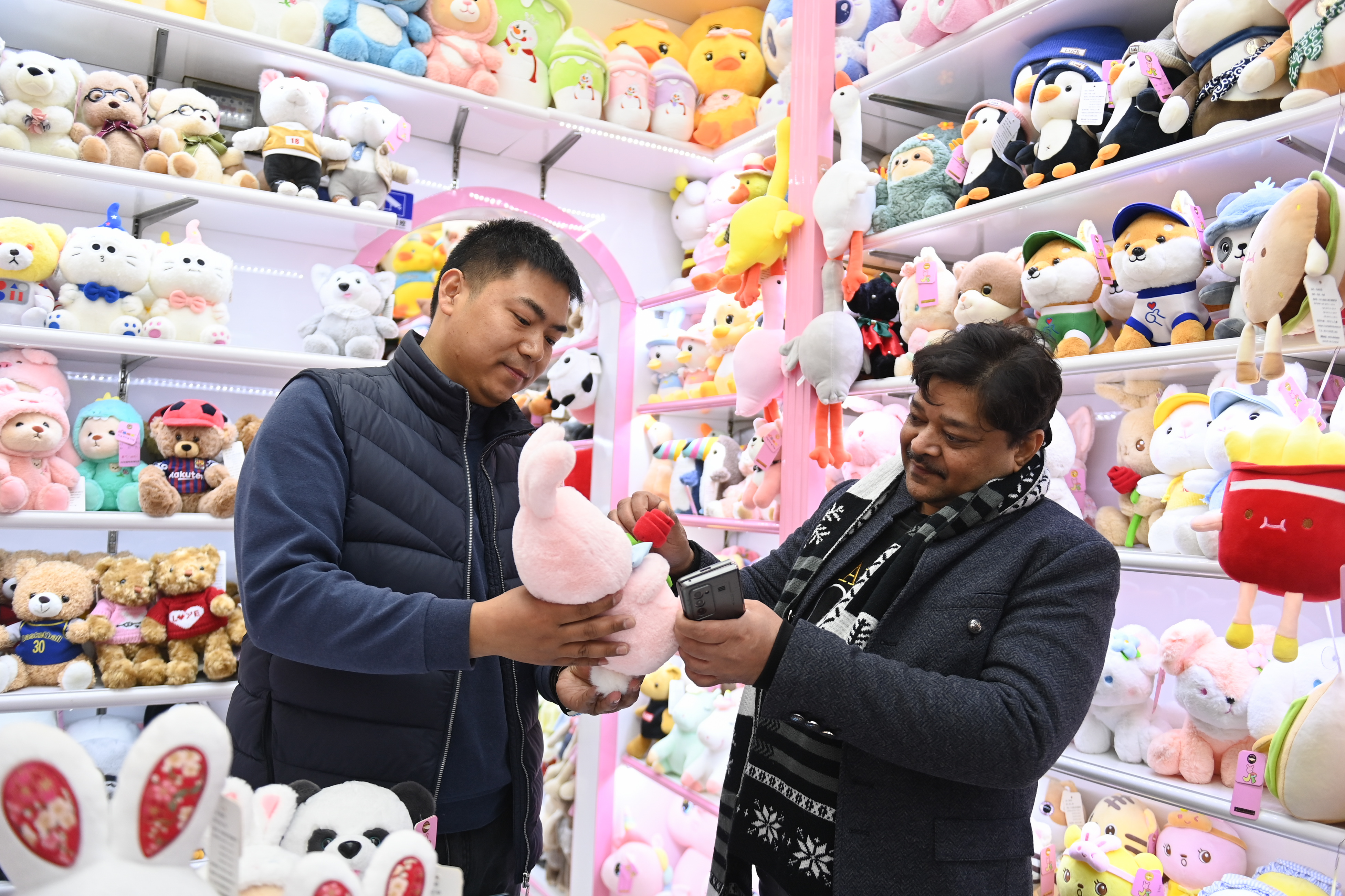 2023年2月2日，來自印度的客商（右）在義烏國際商貿(mào)城的一家玩具店鋪內(nèi)選購。
