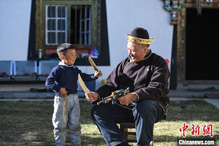 圖為米林縣扎西繞登鄉(xiāng)彩門村64歲的洛桑帶著孫子巴桑在院子的草地上玩耍。　何蓬磊 攝