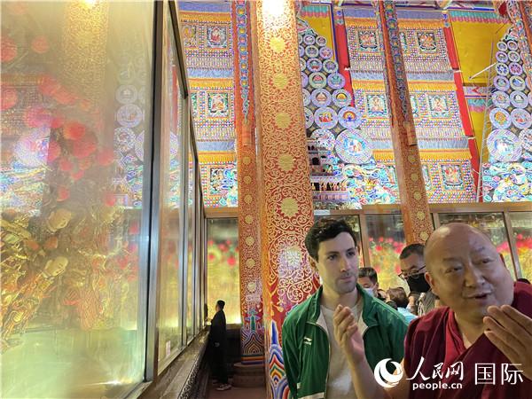 7月25日，省級非物質(zhì)文化遺產(chǎn)項(xiàng)目塔爾寺酥油花的代表性傳承人朋措堅(jiān)參（右）在塔爾寺酥油花館講解酥油花的制作過程。人民網(wǎng) 謝瑩攝