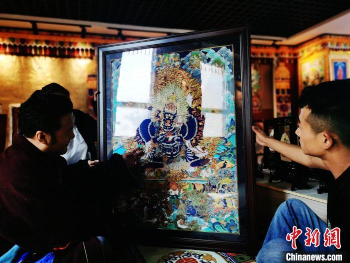 圖為久美尖措(左)與徒弟們展示唐卡作品?！?zhí)砀?攝