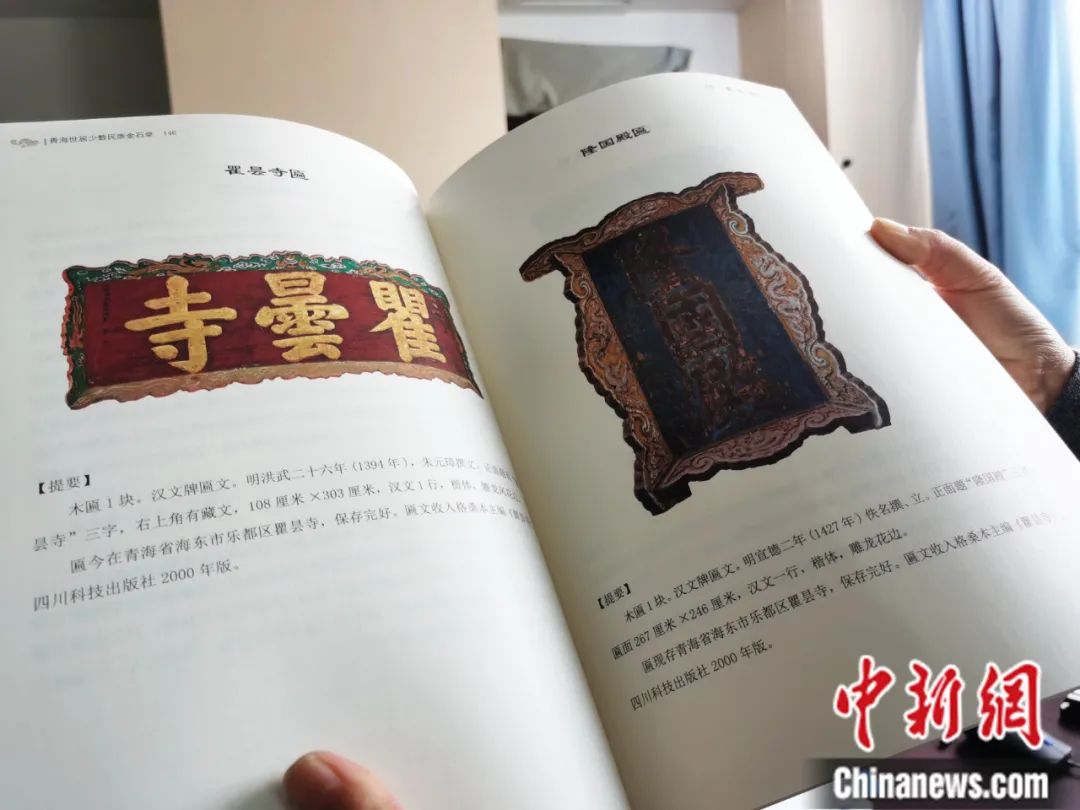 古籍保護(hù)人員展示介紹明代朱元璋撰寫(xiě)的青海瞿曇寺匾(左)的出版書(shū)籍。張?zhí)砀?攝