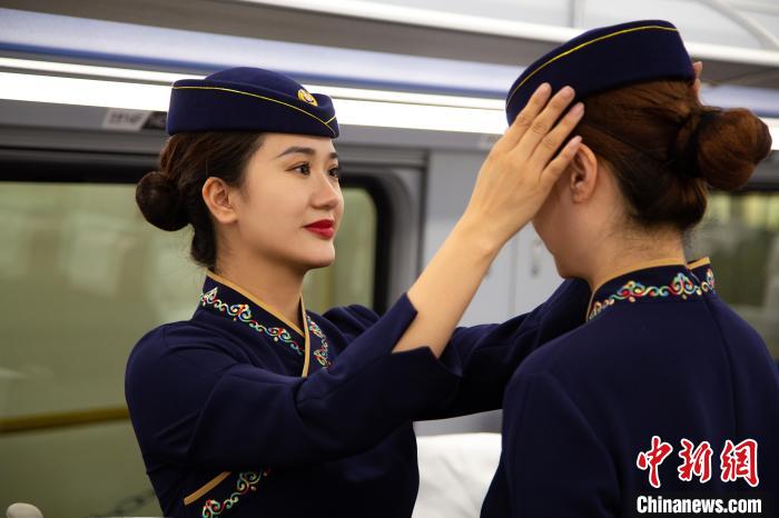圖為青藏鐵路西格段“復(fù)興號(hào)”動(dòng)車組乘務(wù)員互相整理新制服?！±罾?攝