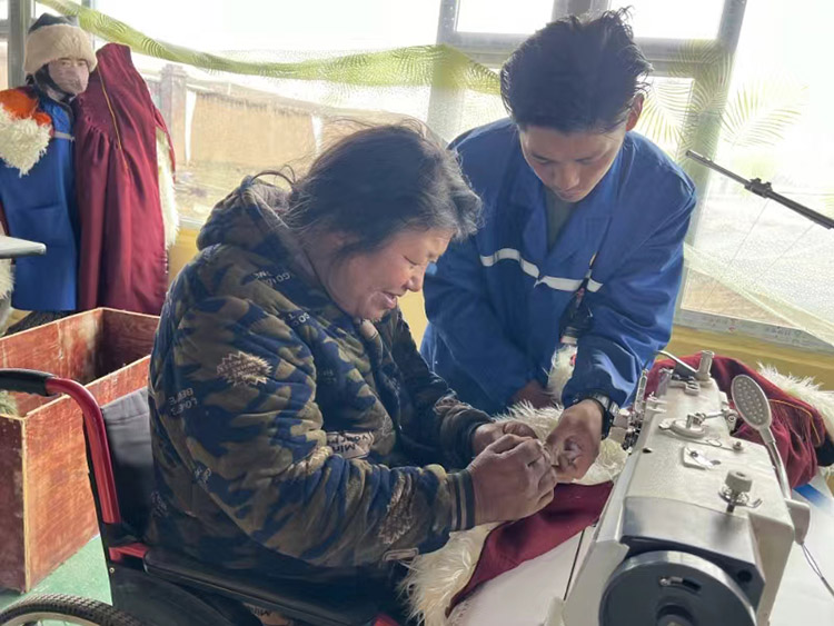 扎西奪爾登幫助殘疾員工裁剪。阿壩州文明辦供圖