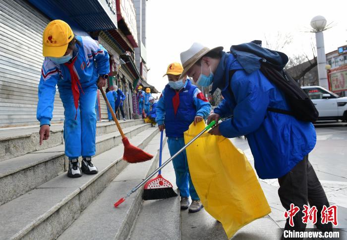 圖為拉薩市小學(xué)生打掃街道?！∝暩聛?lái)松 攝
