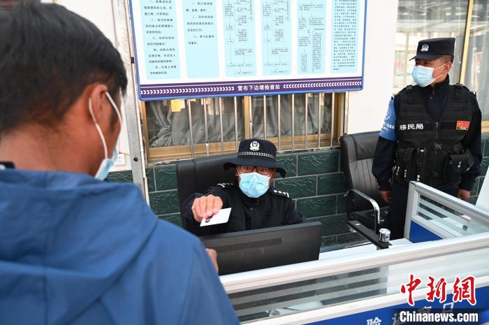 圖為移民管理警察登記完身份信息后將證件歸還給行人?！≮w朗 攝