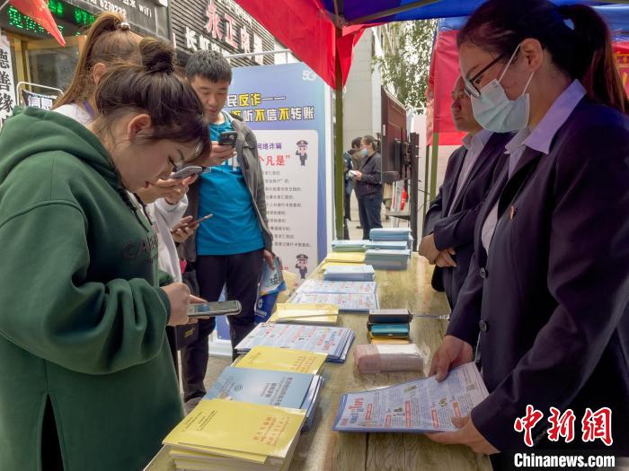 圖為工作人員正在向路過市民介紹國(guó)家反詐中心軟件的功能。　謝牧 攝