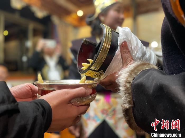 圖為主人在碗中斟滿青稞酒?！∪轿木?攝