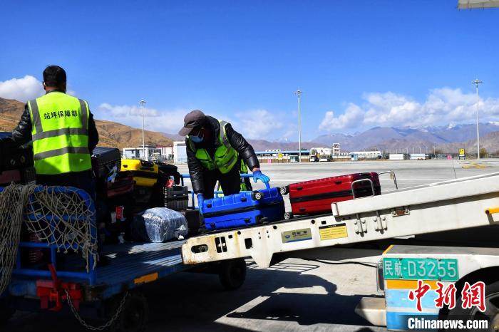 圖為機場工作人員傳送旅客行李箱?！≈芎?攝