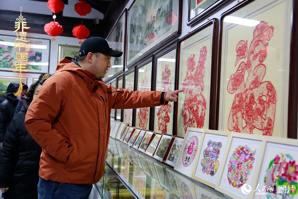 2025年1月23日，游客在天津楊柳青古鎮(zhèn)欣賞傳統(tǒng)剪紙作品，感受指尖上的古老藝術。人民網(wǎng)記者 崔新耀攝